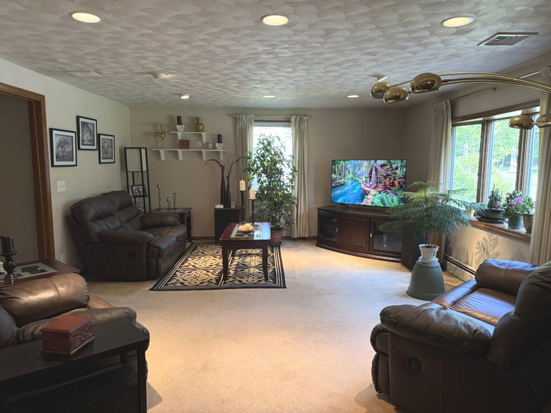     Spacious furnished living room with large flat-panel TV and comfortable reclining leather seating